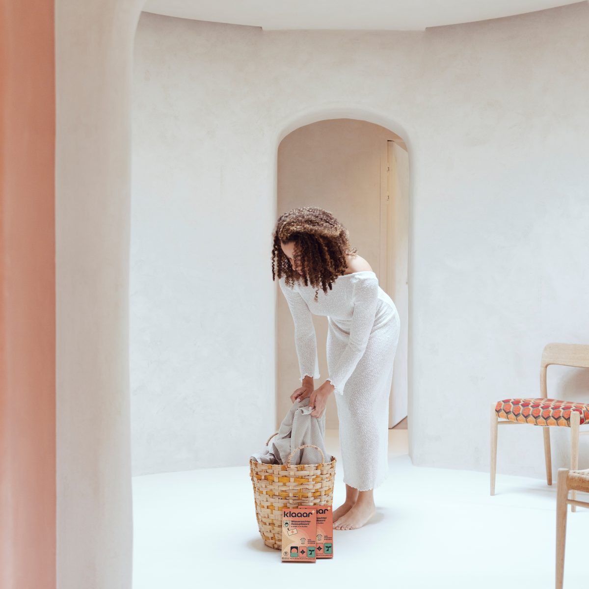 Vrouw met een wasmand en twee doosjes KLAAAR wasverzachter